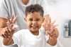 Cute little boy holding his hands out with soapy bubbles on them.