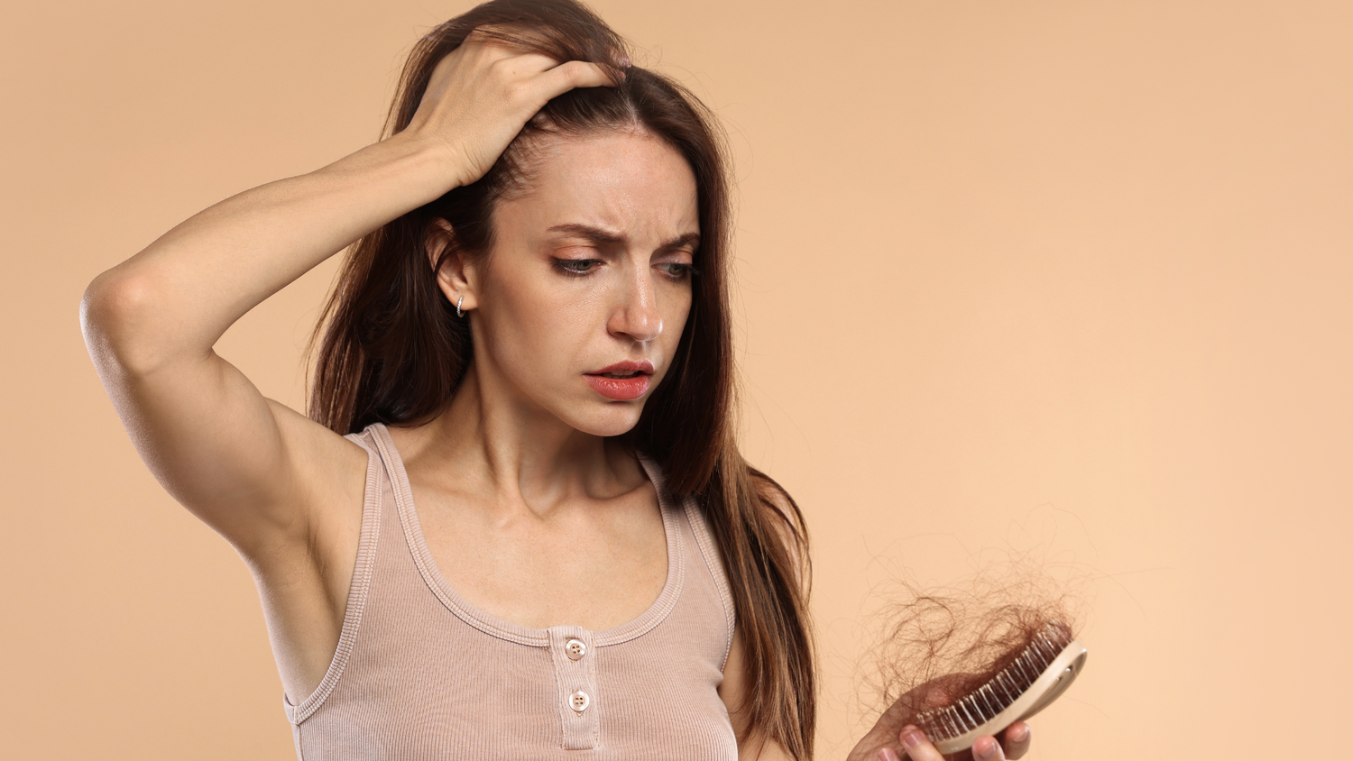 A woman looking at excessive hair loss on her brush, concerned about why her hair is thinning even with treatments.