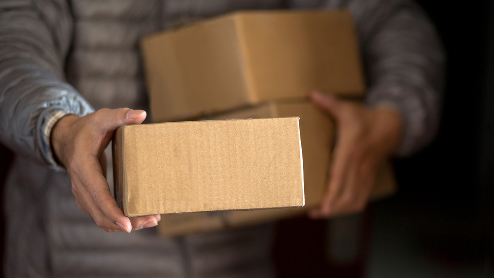 Hands holding a box of ordered Batana hair treatment oil