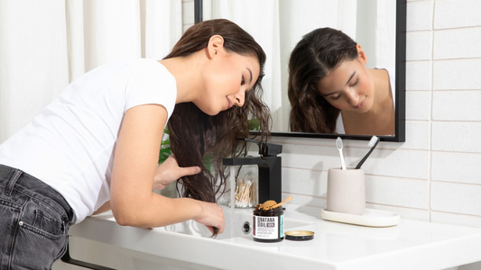Woman applying Hotana 100% unrefined batana oil for thicker, fuller, and healthier hair growth.